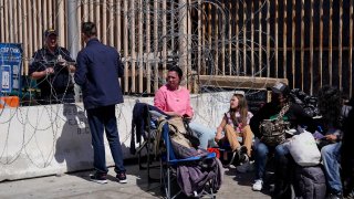 A Russian man talks with a Customs and Border Protection official as he waits with others near the San Ysidro Port of Entry into the United States, in Tijuana, Mexico, Thursday, March 17, 2022. Days earlier, some Russians were being admitted to the U.S. at the San Ysidro crossing, while some Ukrainians were blocked. But by Friday, Russians were denied while Ukrainians were admitted after short waits.