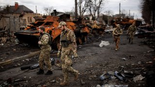 Ukrainian soldiers walk next to destroyed Russian tanks and armored vehicles, amid Russia’s invasion of Ukraine, in Bucha, in Kyiv region, Ukraine, April 6, 2022.