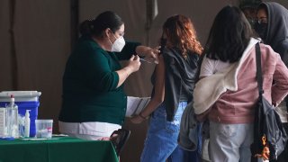 A health worker applies a Pfizer COVID-19 vaccine during a drive for those between the ages of 15 and 17, at the Campo Marte venue in Mexico City, Tuesday, Jan. 11, 2022.