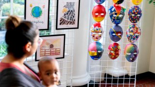 Visitors look at artwork by military connected children on display along the public tour route at the White House in Washington, Friday, April 29, 2022, First lady Jill Biden has added a temporary installation in the East Wing of more then 20 pieces of artwork from military children across the country and those stationed around the world.in honor of the Month of the Military Child.