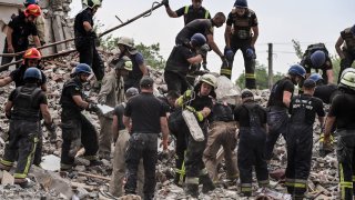 Firefighters and members of a rescue team clear the scene after a building was partially destroyed following shelling, in Chasiv Yar, eastern Ukraine, on July 10, 2022.