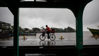 A man rides his bicycle in the rain brought by Tropical Storm Bonnie