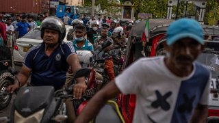 Sri Lankans wait in queue to buy petrol at a fuel station