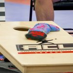 red and purple bean bags sit on a cornhole board with the "ACL" logo