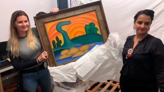 In this photo provided by the Rio de Janeiro Civil Police, officers show artist Tarsila do Amaral's painting titled "Sol Poente" after it was seized during a police operation in Rio de Janeiro, Brazil, Wednesday, Aug. 10, 2022. Police say they seek the arrest of six people accused of stealing 16 artworks, valued at a total of more than 700 million reais ($139 million), stolen from an 82-year-old widow whose daughter orchestrated the theft. (Rio de Janeiro Civil Police via AP)