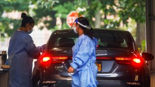 Staff members of the Westchester Medical Center attend a person for the monkeypox vaccine in a drive-through monkeypox vaccination point at the Westchester Medical Center in Valhalla, New York, July 28, 2022.