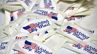 FILE – A woman drops a ballot into a drop box while casting her vote during Maryland’s primary election, Tuesday, July 19, 2022, in Baltimore.