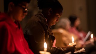 Alexandra Bernier listens to a prayer during a vigil at St. Thomas Episcopal Church