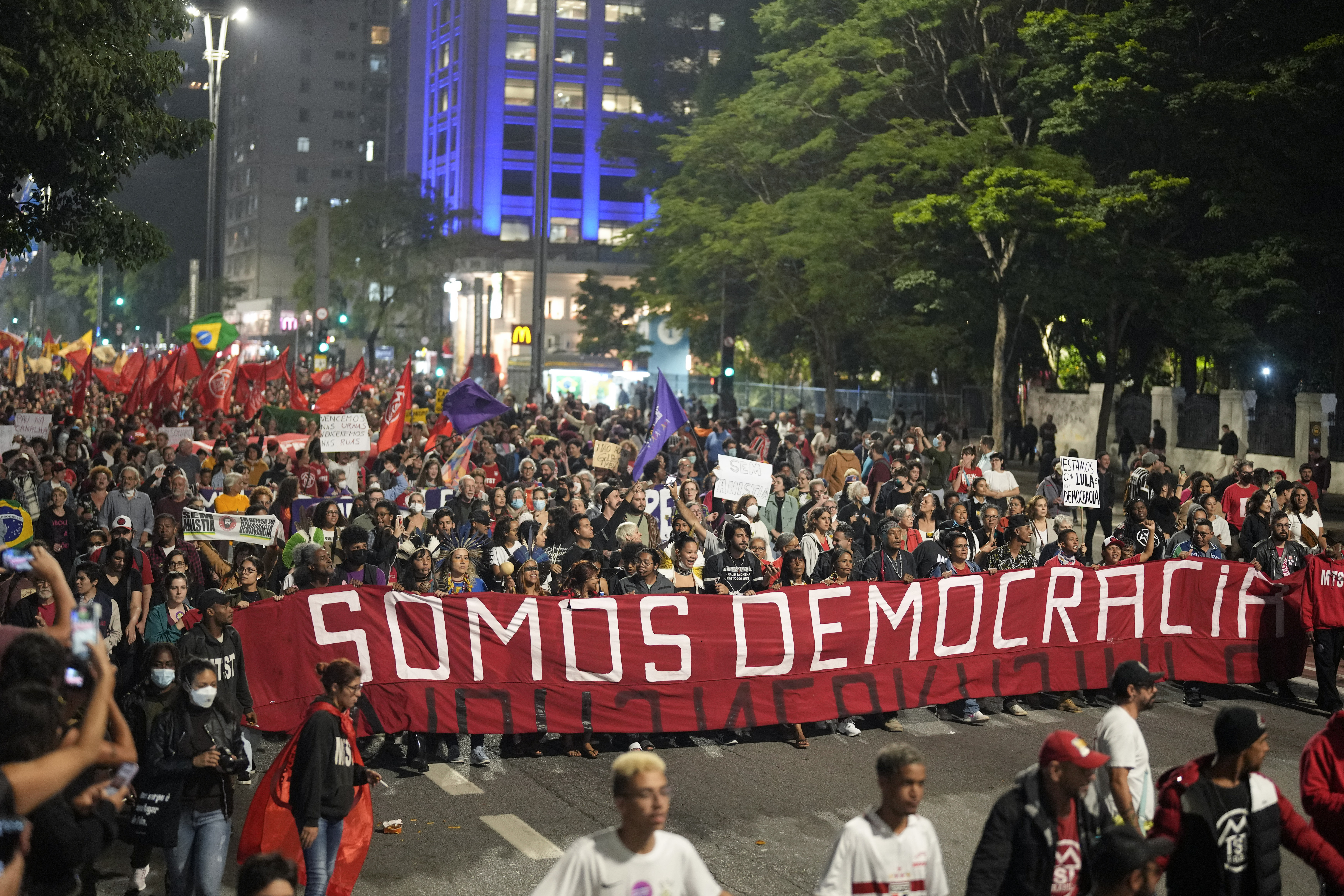 Demonstrators march holding a banner that reads in Portuguese "We are Democracy"