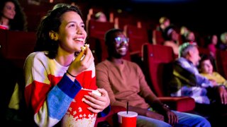 Girl watching a comedy movie at the cinema with her friend.