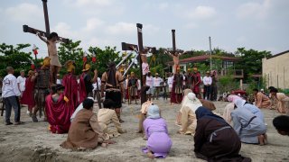 Wilfredo Salvador, center, and two actors stay on crosses during a reenactment of Jesus Christ's sufferings