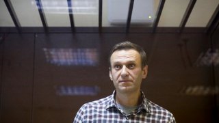 FILE - Russian opposition leader Alexei Navalny stands in a cage in the Babuskinsky District Court in Moscow, Russia, Feb. 20, 2021.
