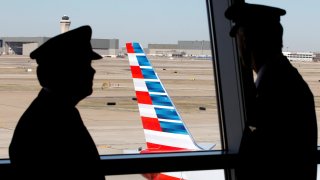 Pilots talk as they look at the tail of an American Airlines aircraft at Dallas-Ft Worth International Airport.