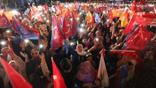 Supporters of Turkish President Tayyip Erdogan wave flags outside the AK Party headquarters after polls closed in Turkey’s presidential and parliamentary elections in Ankara, Turkey on May 15, 2023.