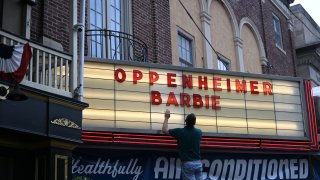 An employee adds letters for upcoming film releases “Oppenheimer” and “Barbie” to a marquee at the Colonial Theater on July 16, 2023 in Phoenixville, Pennsylvania.