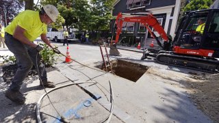 Richie Nero, left, of Boyle & Fogarty Construction, works on removing a old lead residential water supply line, outside a home where service was getting upgraded to copper, Thursday, June 29, 2023, in Providence, R.I. Health and environmental groups have been fighting for lead-free water to drink in Providence for at least a decade. (AP Photo/Charles Krupa)