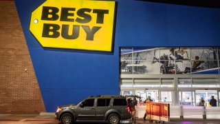 A shopper pushes a cart with a TV in front of a Best Buy store in Chicago, Illinois, November 25, 2022.