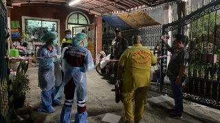 Forensic officers and a rescue worker arrive at a house where a woman and her two sons were killed and her husband was found severely injured, in Samut Prakan province on Aug. 28, 2023.