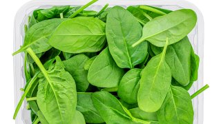 Spinach leaves  in a plastic package isolated on white background. Green Spinach leaves box Top view.