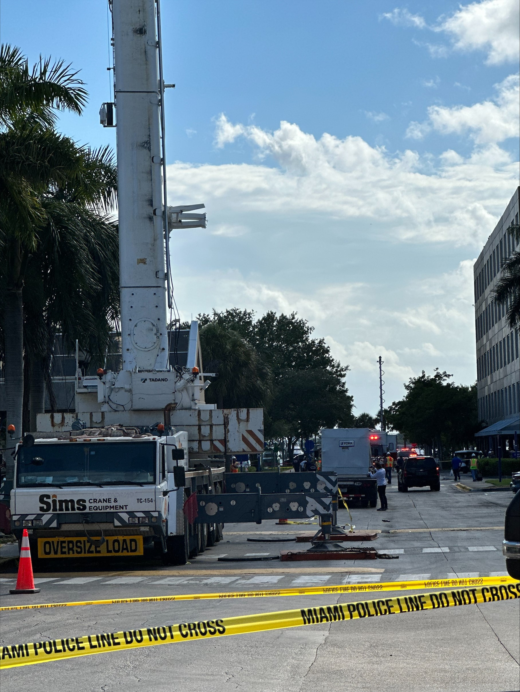 Picture shows police tape in the foreground as a white truck customized with a crane sits in the background