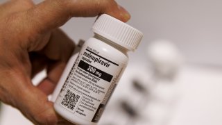 A worker handles a bottle of Merck & Co. and Ridgeback Biotherapeutics LPs Molnupiravir antiviral medication in a warehouse in Shoham, Israel, on Jan. 18, 2022. A fourth dose of the Pfizer-BioNTech vaccine was insufficient to prevent infection with the omicron variant of Covid-19, according to preliminary data from a trial in Israel released Monday. Photographer: Kobi Wolf/Bloomberg via Getty Images