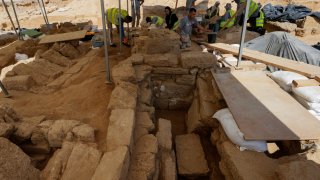 Palestinian archaeologists remove sand from graves at the Roman cemetery