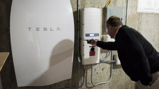 A customer inspects a Tesla Motors Inc. Powerwall unit inside a home.