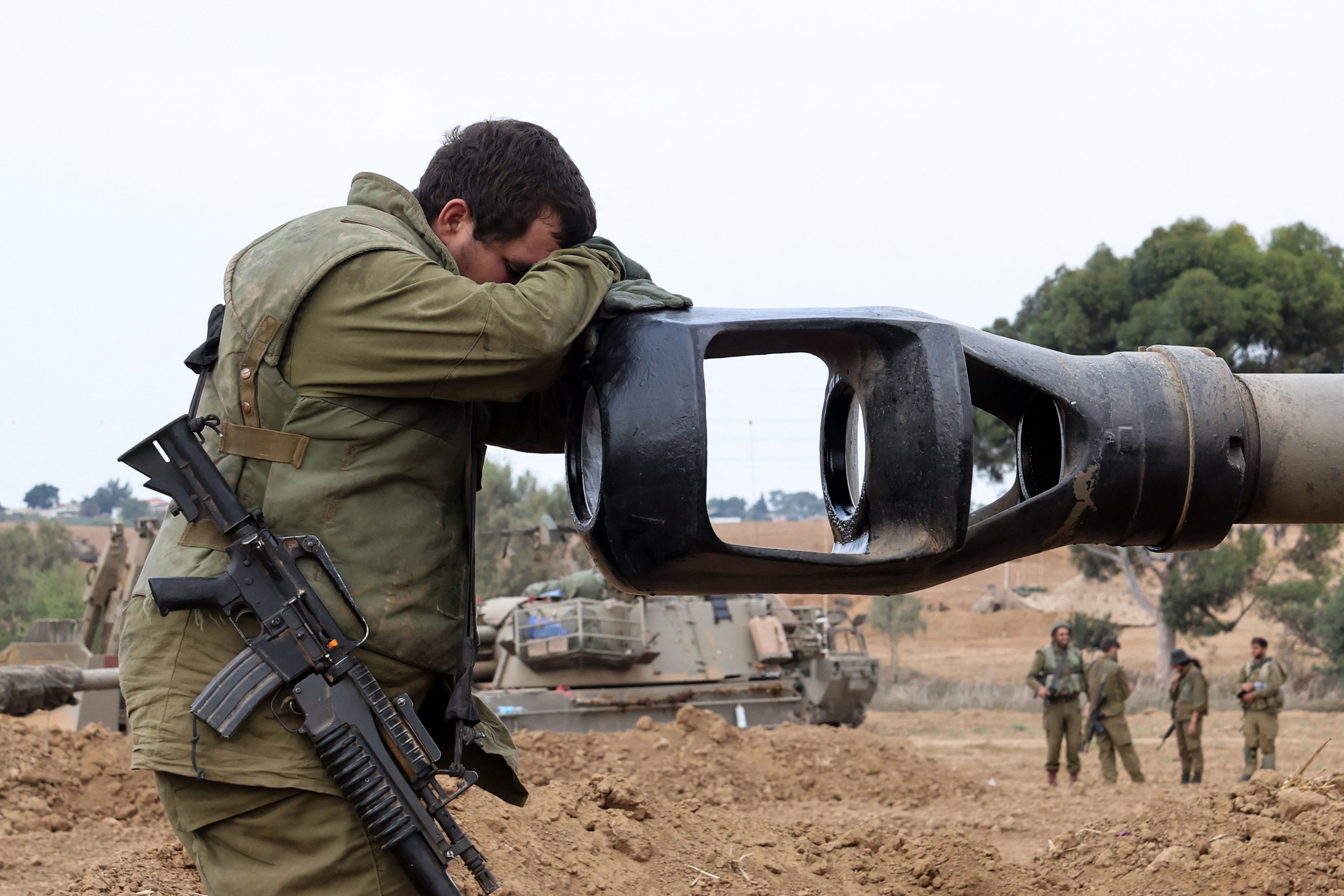 An Israeli soldier rests his head on an artillery gun barrel of an armored vehicle as Israeli soldiers take positions near the border with Gaza in southern Israel on Oct. 9, 2023.