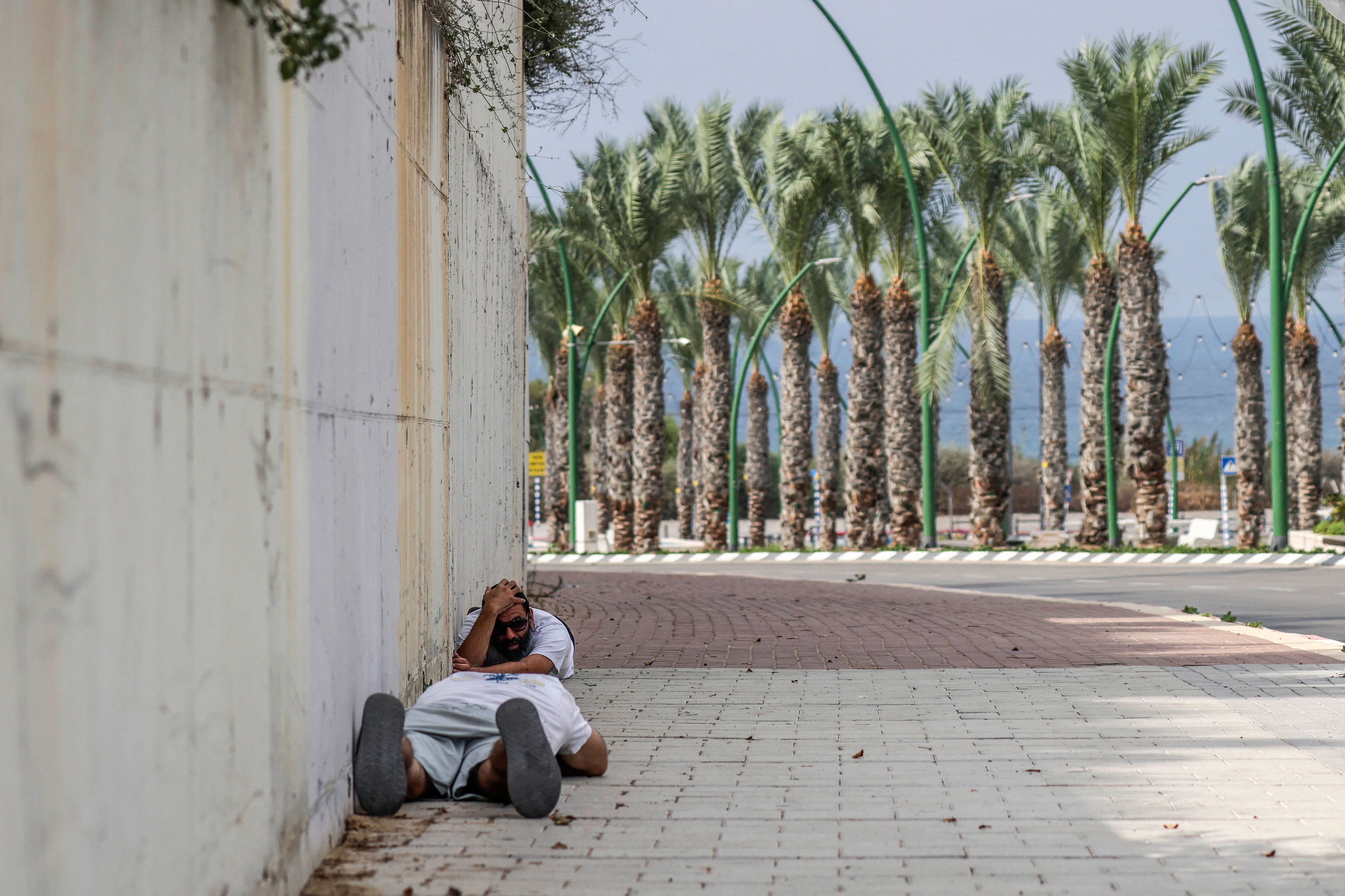 People duck for cover upon hearing sirens warning of incoming fire in the southern Israeli city of Ashkelon on Oct. 11, 2023.