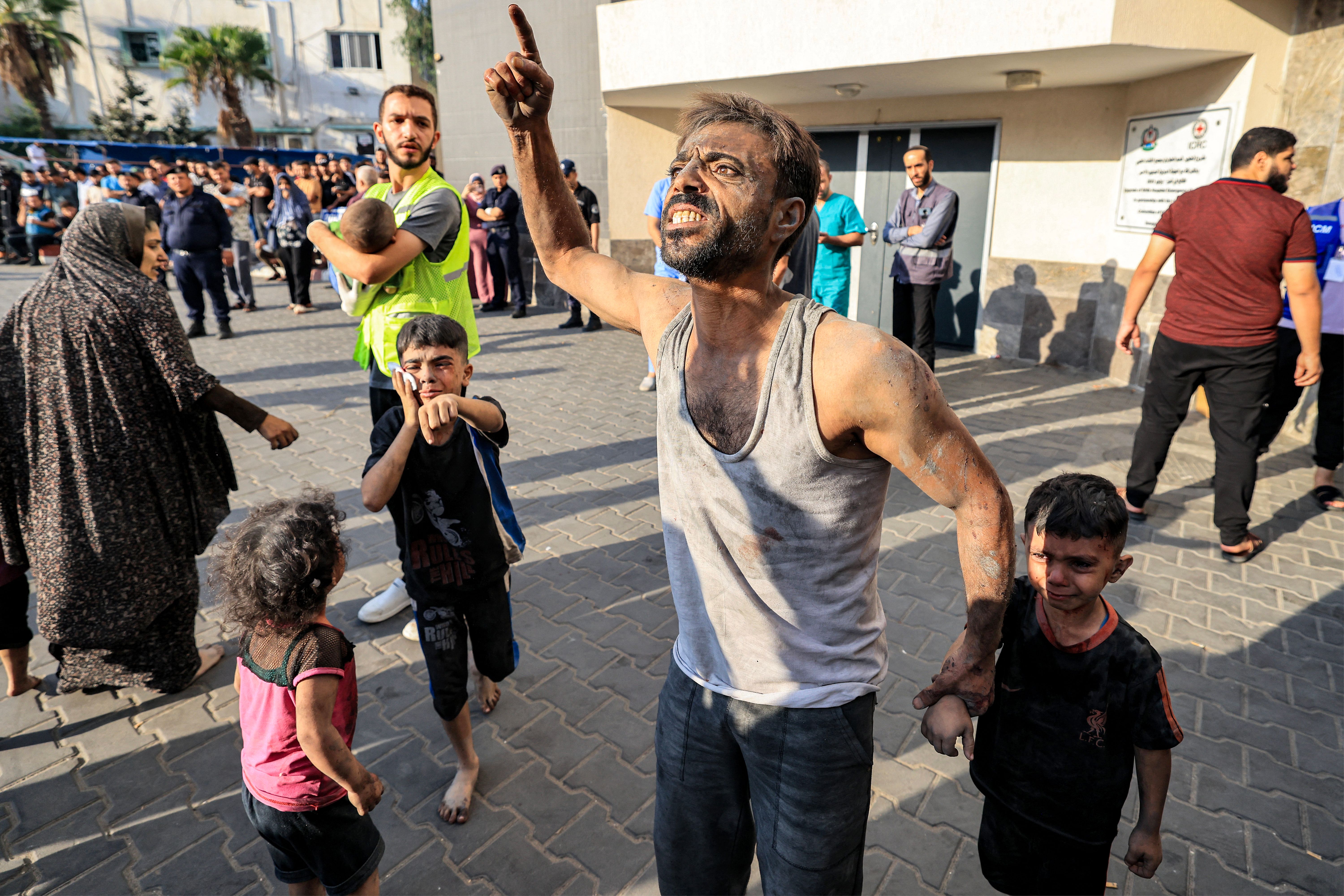 A Palestinian man with a child reacts outside al-Shifa hospital in Gaza City on Oct. 12, 2023 as raging battles between Israel and the Hamas movement continue for the sixth consecutive day.