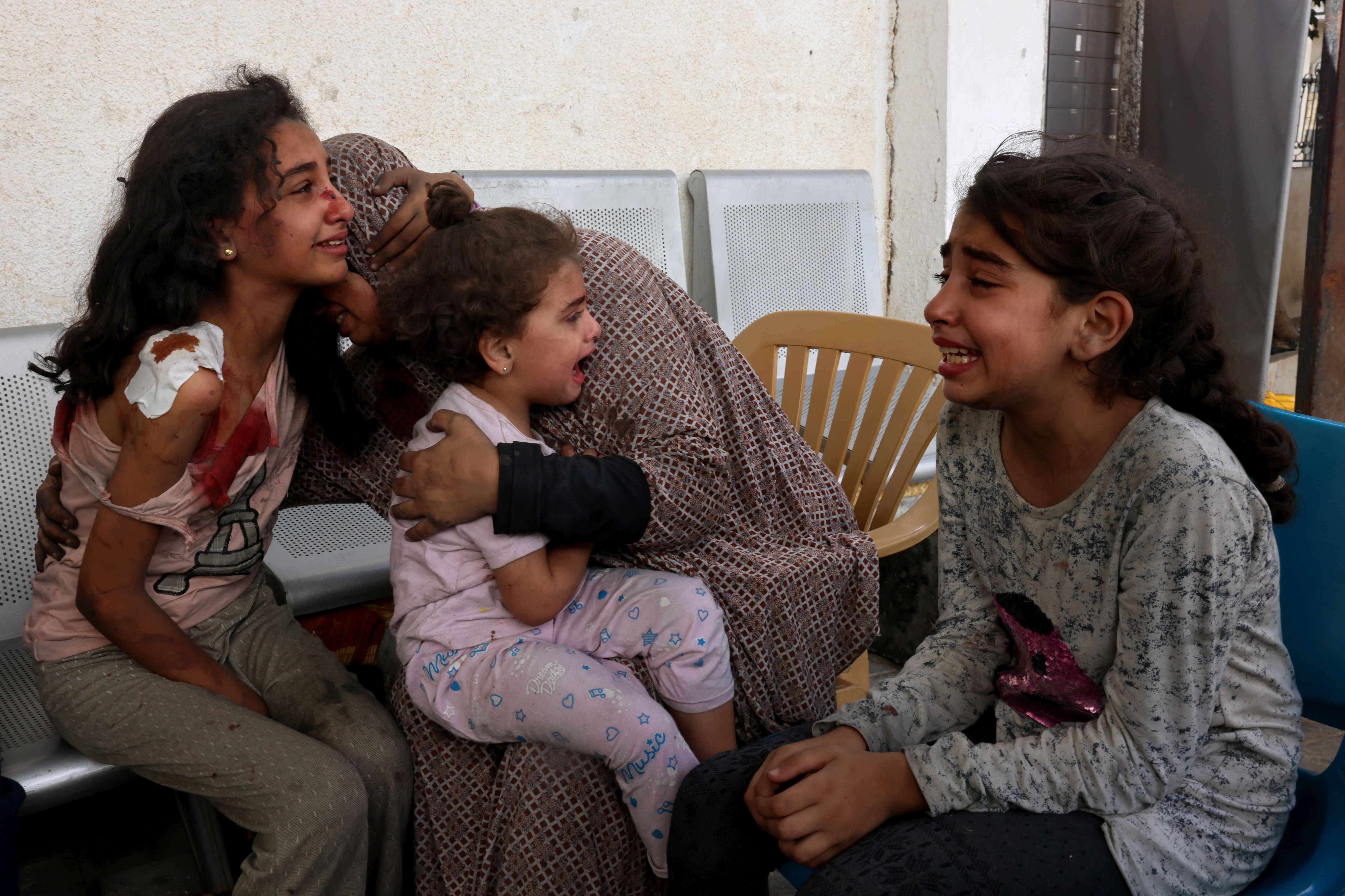 A woman comforts injured Palestinian girls waiting at the hospital to be checked, as battles between Israel and the Hamas movement continue for the sixth consecutive day, in the city of Rafah, in the southern Gaza Strip on Oct. 12, 2023.
