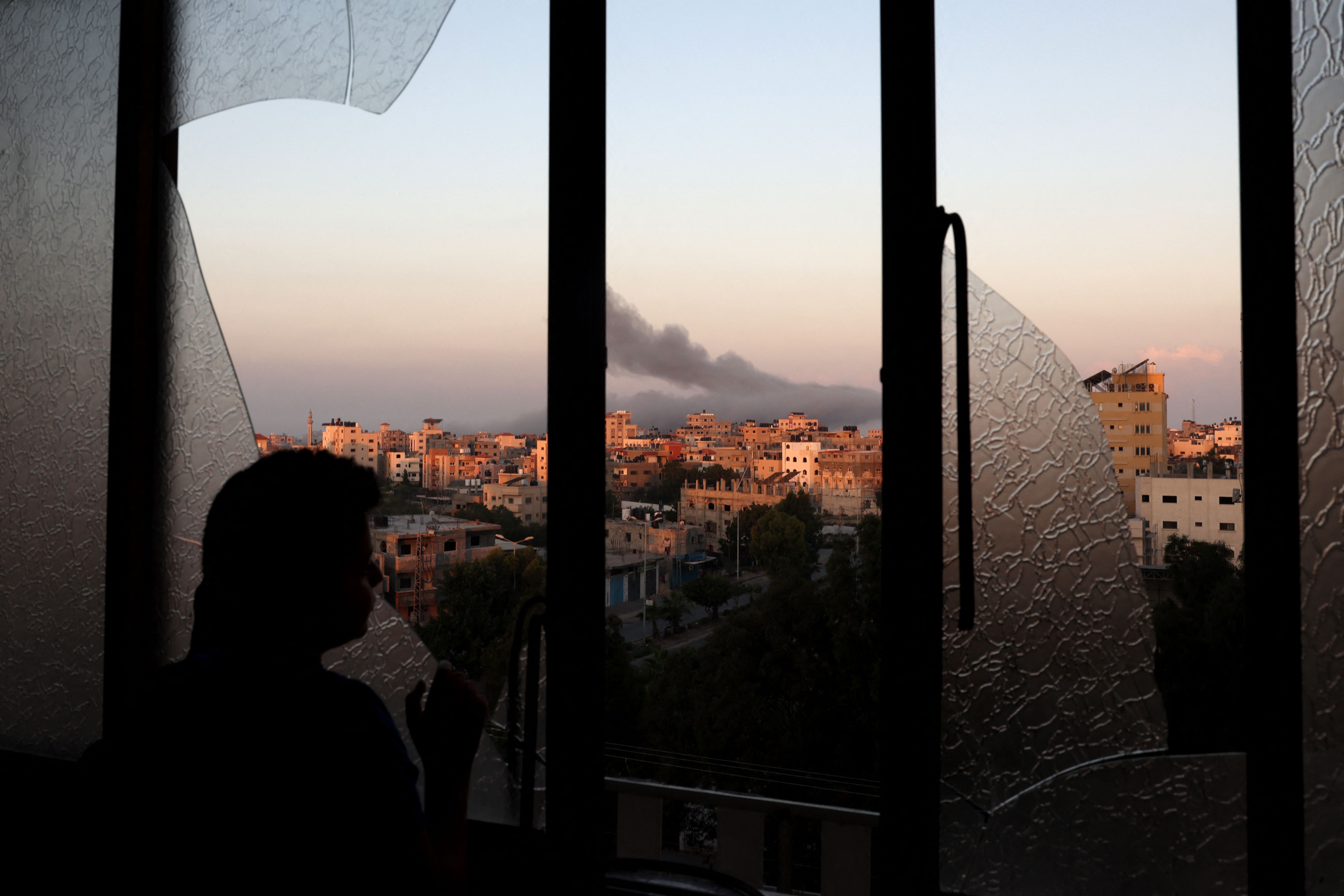 A Palestinian child watches as smoke billows on the horizon after an Israeli air strike in Gaza City on Oct. 13, 2023.
