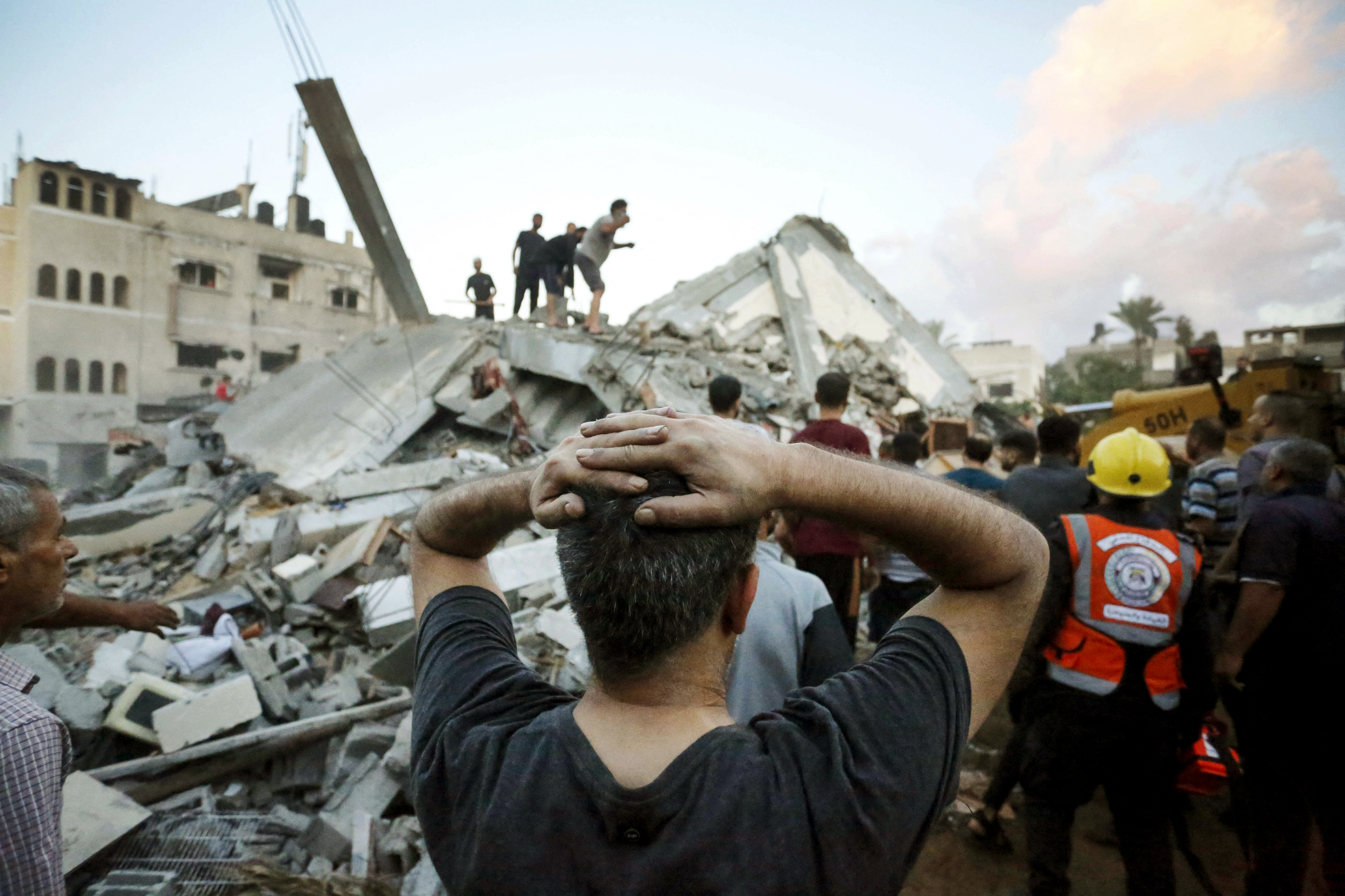 A man reacts as he watches rescuers and civilians remove the rubble of a home destroyed following an Israeli attack on the town of Deir Al-Balah, in the central Gaza Strip, on Oct. 15, 2023.