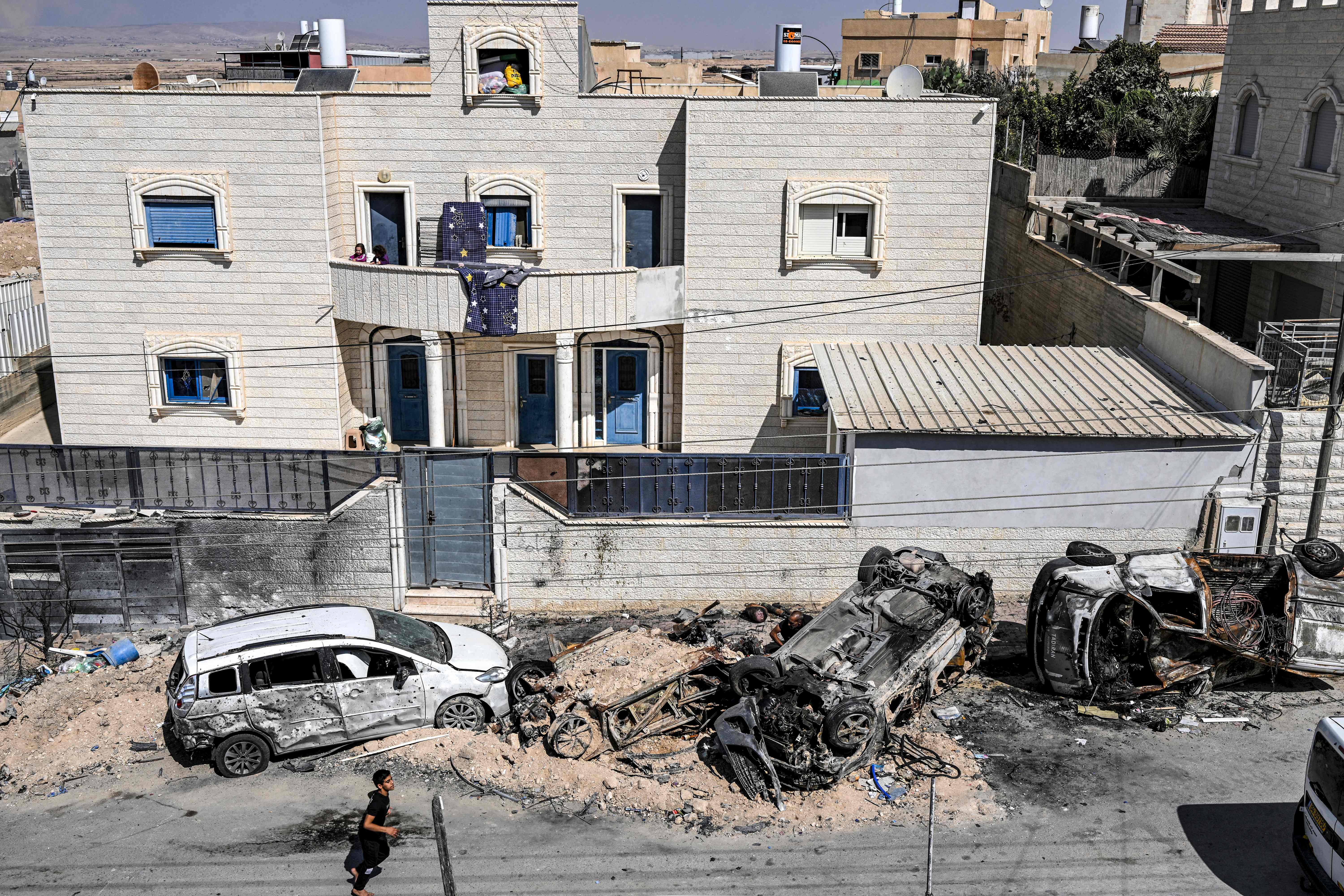 Members of the Bedouin community inspect vehicles destroyed in a rocket attack allegedly fired from the Gaza Strip in the village of Arara in the Negev Desert, on Oct. 14, 2023.