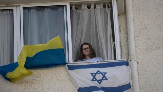 Tatyana Prima, who fled Mariupol, Ukraine, poses for a portrait with her national flag and the Israeli flag