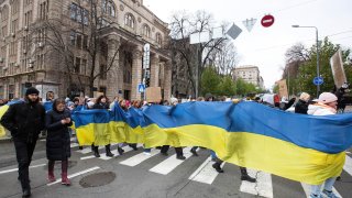 Protesters carry a large flag of Ukraine during a demonstration.