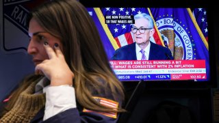 A trader works, as a screen displays a news conference by Federal Reserve Board Chairman Jerome Powell following the Fed rate announcement, on the floor of the New York Stock Exchange (NYSE) in New York City, U.S., December 13, 2023. 