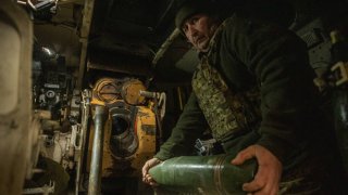 DONETSK OBLAST, UKRAINE – DECEMBER 18: A crewmember of the 122-mm self-propelled howitzer 2S1 Gvozdika loads a projectile into the howitzer for firing onto Russian positions near the occupied Ukrainian city of Bakhmut on December 18, 2023 in Donetsk Oblast, Ukraine. Bakhmut and its surroundings continue to be places of most fierce battles since the beginning of the full-scale Russian invasion. Ukrainian artillery, under the adjustment of UAVs, fires on enemy dugouts, firing positions and logistical routes, destroying the offending Russian infantry and supporting the Ukrainian assault operations. (Photo by Roman Chop/Global Images Ukraine via Getty Images)