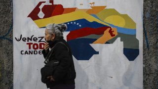 A woman walks next to a mural of the map of Venezuela that includes the Essequibo territory