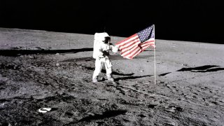 Apollo 12 – NASA, 1969. During the first extravehicular activity, astronaut Charles Conrad, Jr., Apollo 12 commander, releases the United States flag on the lunar surface. Boot prints from the astronauts can be seen in the image as well, November 19, 1969. Artist NASA. (Photo by Heritage Space/Heritage Images via Getty Images)