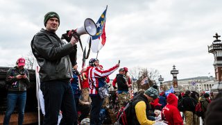 FILE - A pro-Trump protester wearing a Philadelphia Eagles hat leads a crowd in a chant with a bullhorn in front of the Capitol on Jan. 6, 2021.