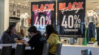 A family eats lunch near a store advertising a Black Friday sale at the Pentagon City Mall in Arlington, Virginia, on November 22, 2023. (Photo by ANDREW CABALLERO-REYNOLDS / AFP) (Photo by ANDREW CABALLERO-REYNOLDS/AFP via Getty Images)