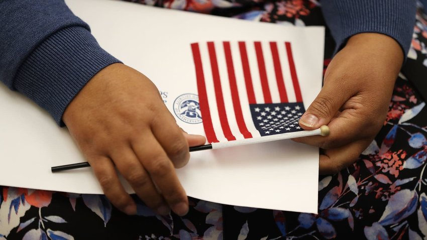 A person holds an American flag as they participate in a ceremony to become an American citizen during a U.S. Citizenship & Immigration Services naturalization ceremony at the Miami Field Office on August 17, 2018 in Miami, Florida.