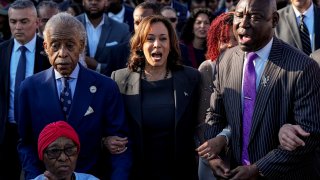 The Rev. Al Sharpton, Vice President Kamala Harris and Attorney Ben Crump walk and sing across the Edmund Pettus Bridge