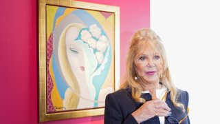 Pattie Boyd poses next to the original artwork by E. Frandsen De Schomberg, used for the cover of Derek and the Dominoes album 'Layla and Other Assorted Love Songs' as part of The Pattie Boyd Collection at Christie's, in London, Thursday, March 14, 2024. The artwork is estimated to sell £40,000-60,000. (AP Photo/Alberto Pezzali)