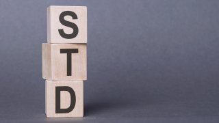 Wooden cubes with letters STD on violet background