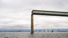 A temporary channel for smaller vessels below a remaining piece of the Francis Scott Key Bridge. 