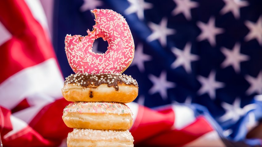 Sprinkle donuts stacked in front of an American flag.