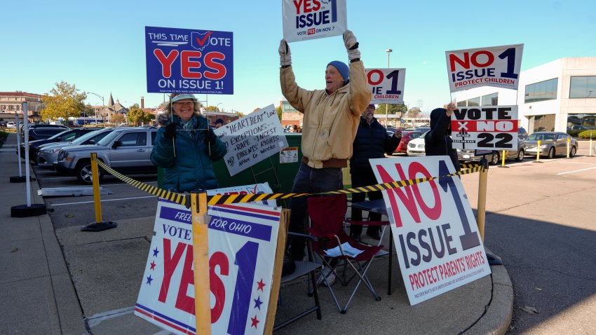 People gather in the parking lot of the Hamilton County Board of Elections as people arrive for early in-person voting