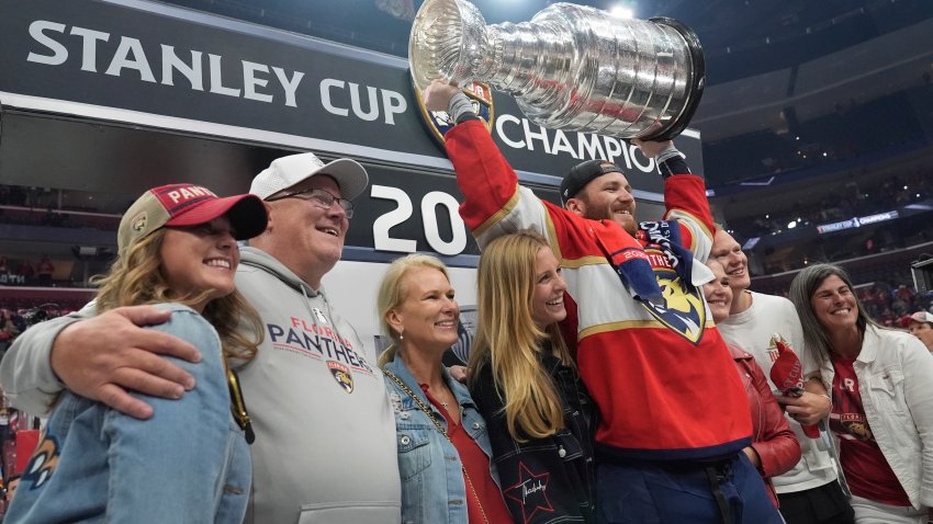 Florida Panthers Matthew Tkachuk raises the Stanley Cup trophy surrounded by his family